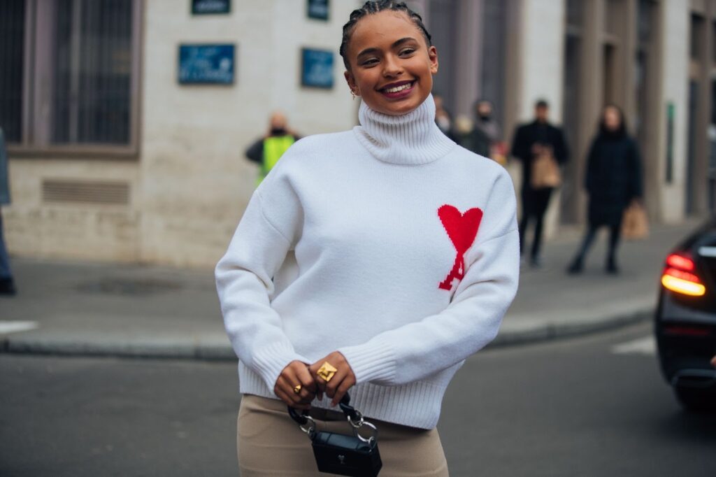 Fröhliche Frau in einem weißen Pullover mit Herz Photo by Christian Vierig/Getty Images