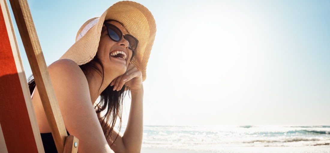 lächelnde Frau im Strohhut am Strand