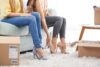 Zwei Frauen sitzen auf dem Sofa und probieren High Heels an