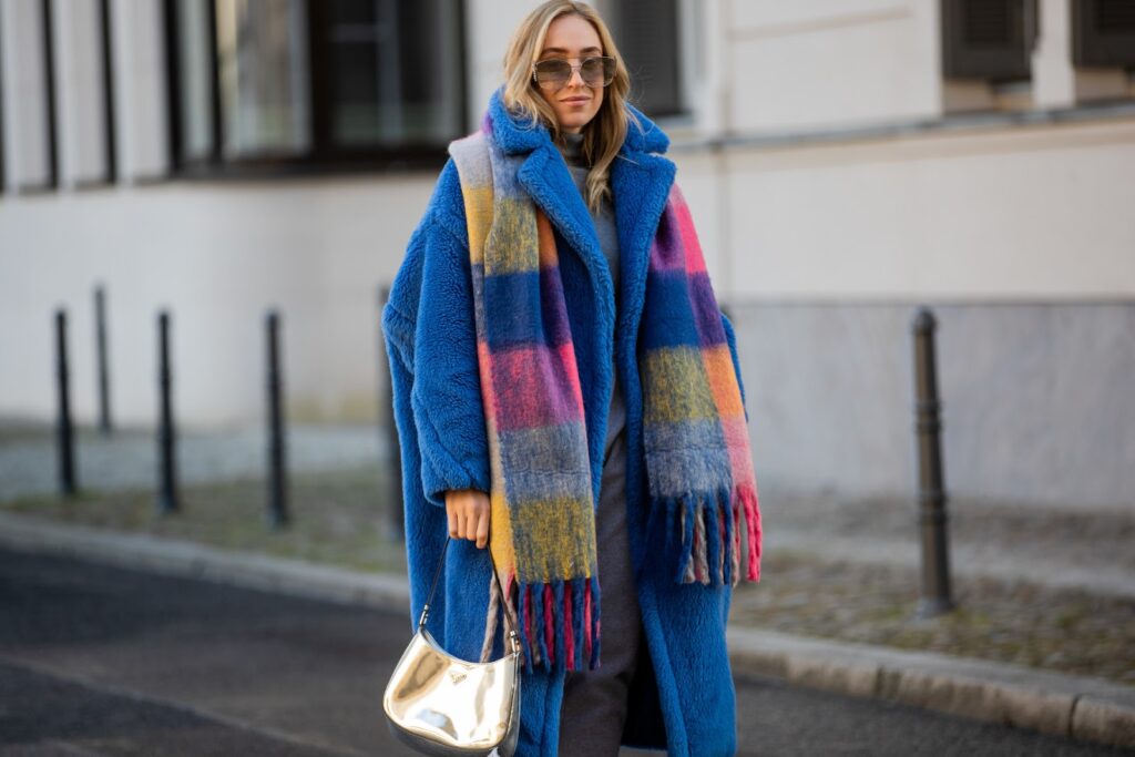 Frau in einem blauen Mantel und mit einem bunten Schal