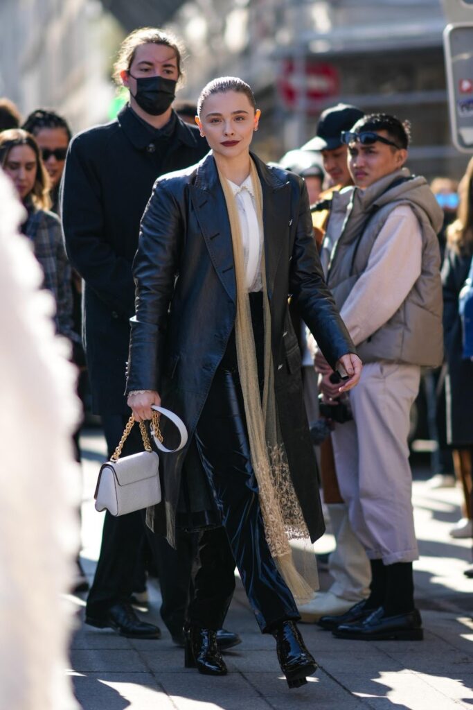 Chloe Grace Moretz in einem glänzenden langen Mantel und einer Lederhose