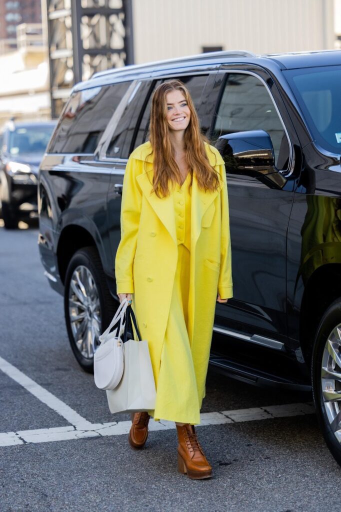 Olivia Jauretche im gelben Look, in braunen Schnürstiefeletten und mit grauer Handtasche