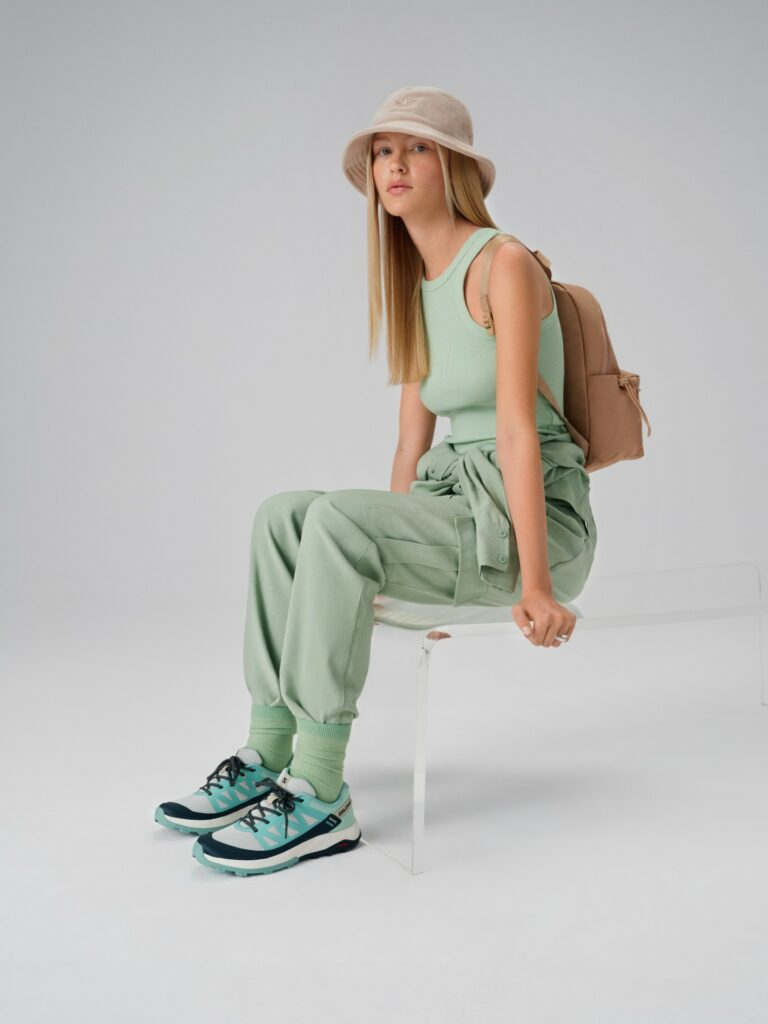 Model im Streetwear-Stil mit beiger adidas-Mütze und Salomon-Schuhen
