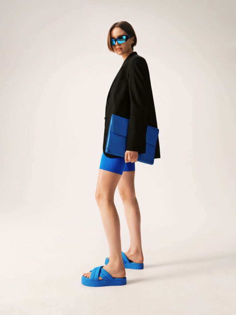 Styling mit schwarzem Blazer und passender blauer Shorts und gleichfarbigen Plateau-Flip-Flops.
