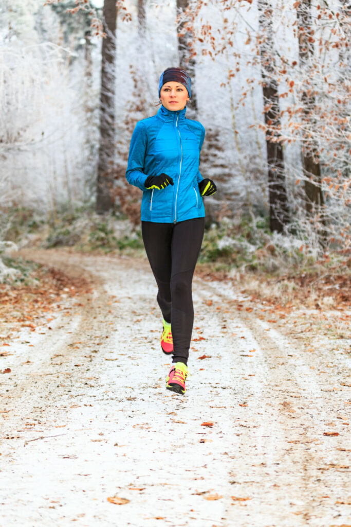 eine junge Frau joggt durch den winterlichen Wald