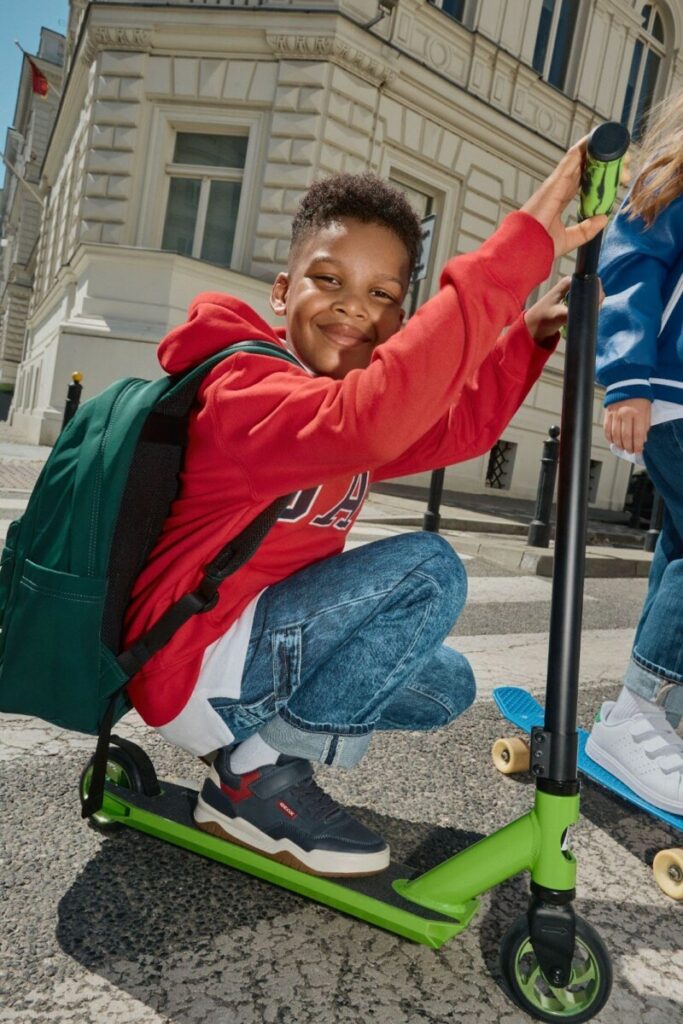 Junge mit einem Rucksack und einem Tretroller