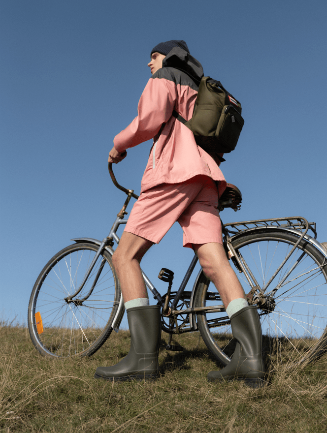 Mann mit Fahrrad in Gummistiefeln und Schal von Hunter